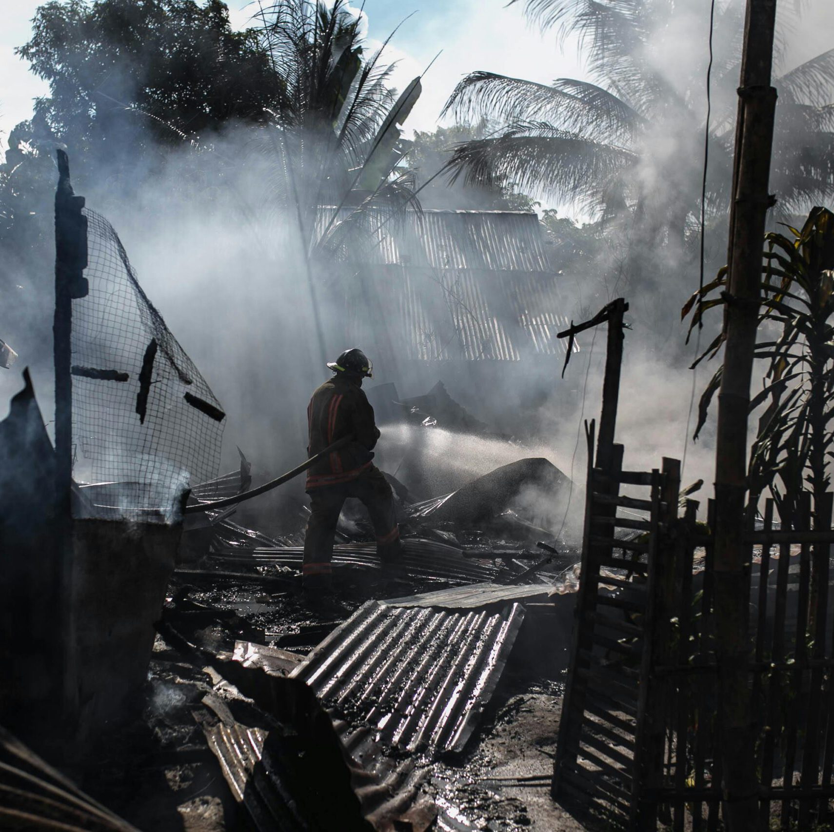 Brave firefighters battle a blaze amidst thick smoke in an outdoor setting.